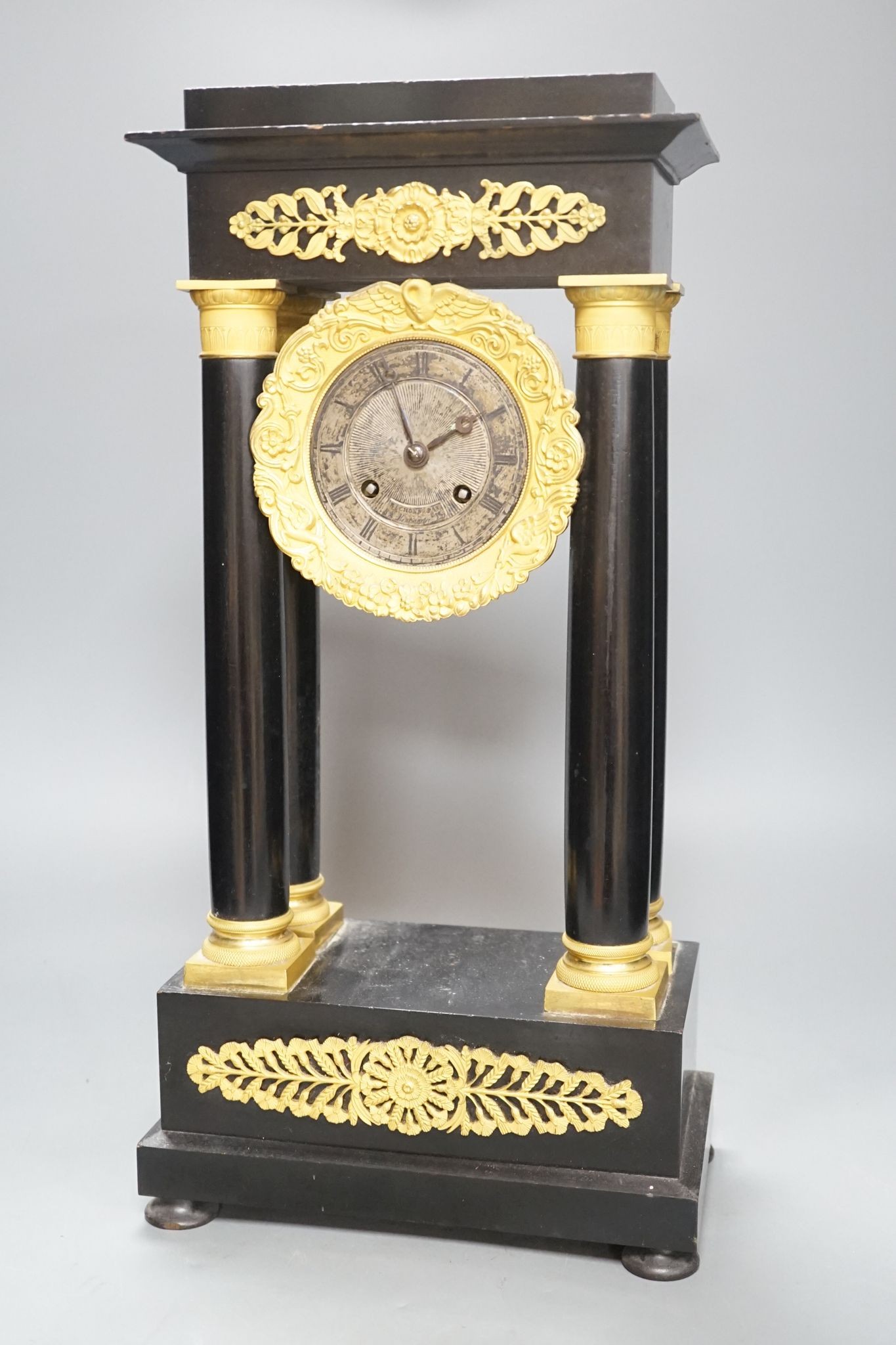 A 19th century French ebonised portico mantel clock with brass mounts, 47 cms high.